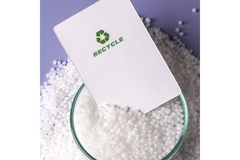 Image Recycle symbol card on white plastic pellets